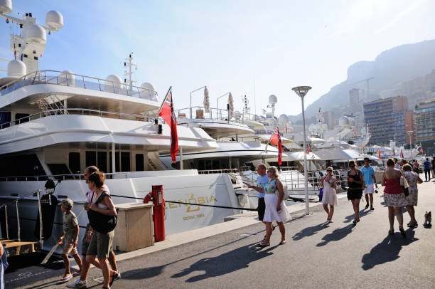 Monte Carlo, Monaco  -October 23, 2025: This stock photo showcases the picturesque harbour of Monte Carlo, Monaco, dotted with luxury yachts and sailboats. The image highlights the glamour and elegance of Monaco’s Mediterranean coastline, with the city’s modern and historic buildings rising above the marina. Monte Carlo Harbour is world-renowned for hosting prestigious yachting events, attracting celebrities, affluent travelers, and sailing enthusiasts. The combination of sparkling water, luxury vessels, and scenic urban backdrop reflects the city’s reputation for wealth, leisure, and Mediterranean charm.