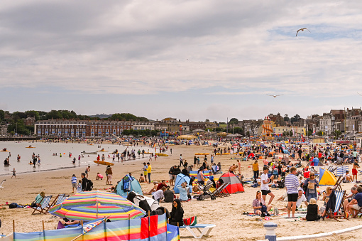 Weymouth, England - July 2021: Crowds of people on the sandy beach in  the tourst resort of Weymouth in Dorset.