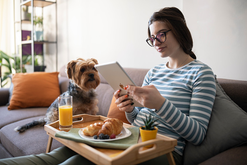 Woman with glasses using a digital tablet while having a breakfast