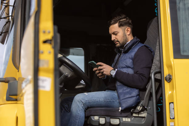 istock Truck driver sitting in cabin while typing on phone 1359025534