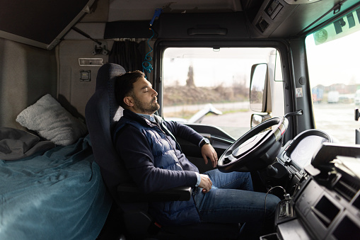 Tired truck driver taking break during driving and napping on driver's seat