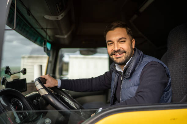 istock Truck driver sitting in cabin and looking at camera 1359025823