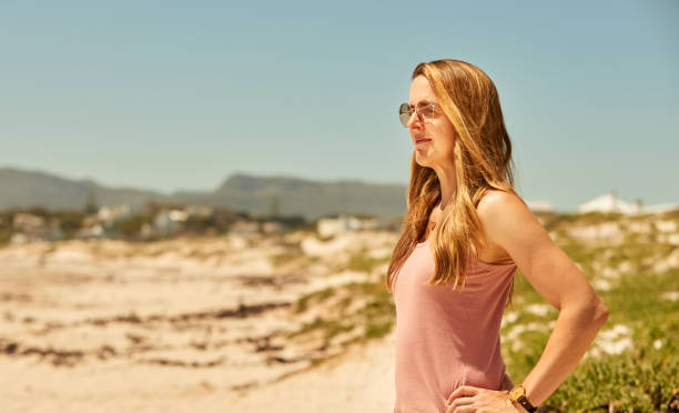 istock Attractive young woman standing on the beach in summer time 1359026026