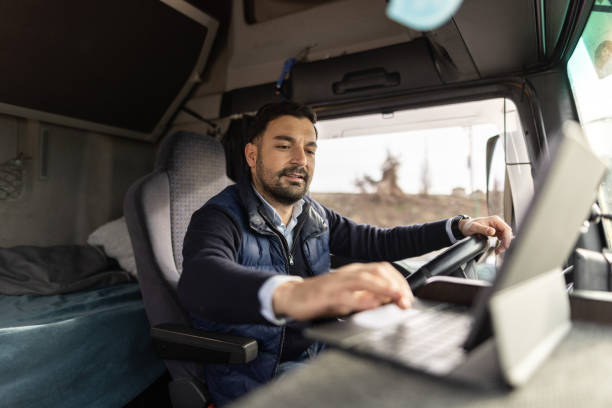 Truck driver typing destination on tablet while sitting in cabin