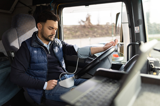 Worried truck driver sitting in cabin and measuring blood pressure