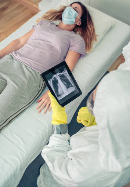 istock Doctor in protective suit examining x-ray of patient on tablet 1359028151