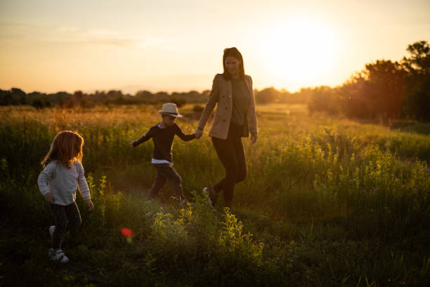 istock Mother walking across grass field with her two kids 1359028744