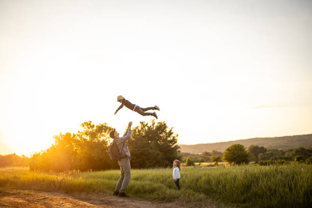 istock Father spending time with his two kids in nature while throwing son into air 1359028904