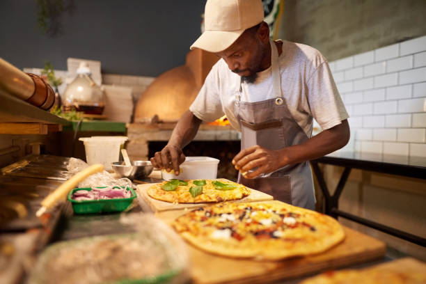 chef cuisinier préparant une pizza dans un restaurant - chef restaurant cooking african descent photos et images de collection