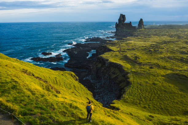 hombre excursionista con chaqueta amarilla de pie en la cima de la roca en un parque al aire libre en islandia. londrangar - snaefellsnes fotografías e imágenes de stock