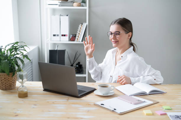 istock Cheerful woman greeting colleagues while talking on laptop home. 1359033219