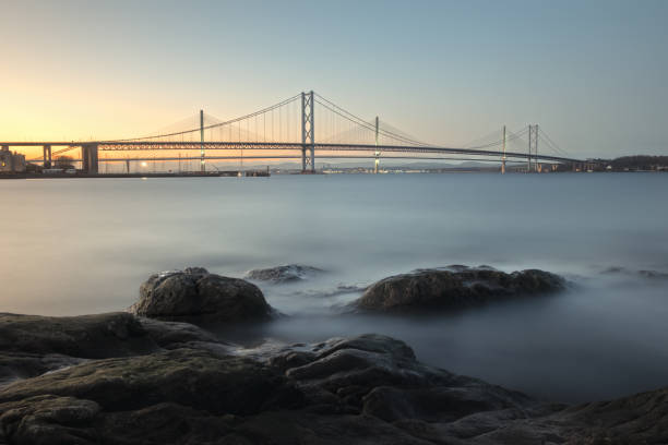 View of a stone coast of the sea and bridges in the background stock photo