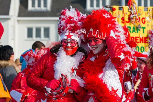 Maastricht, Limburg, Netherlands, february 10th 2013, portrait of two cheerful women wearing white/red ceremonial make-up and a costume with feathers, walking along in the sunday carnaval parade in the downtown district of Maastricht - with over 3 million annual visitors the city is a popular travel destination