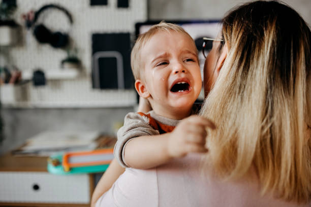 istock Little boy crying in his mother arms 1359041632