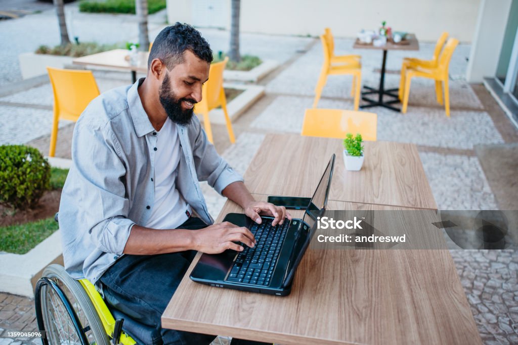 wheelchair man working on the computer in the cafeteria Wheelchair Stock Photo