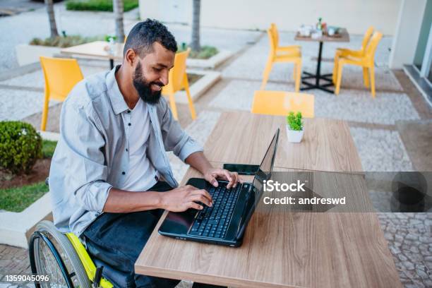 Wheelchair Man Working On The Computer In The Cafeteria Stock Photo - Download Image Now