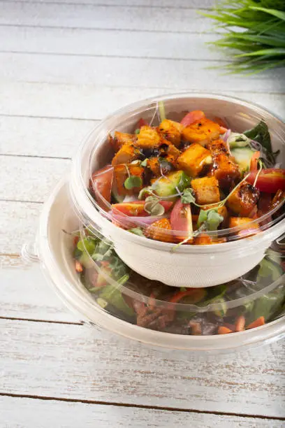 A view of a stack of salad bowls in to-go containers.