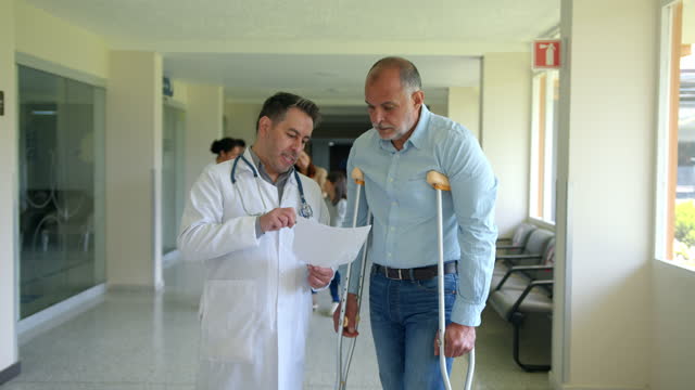 Orthopedist explaining a prescription to senior patient using crutches at the hospital