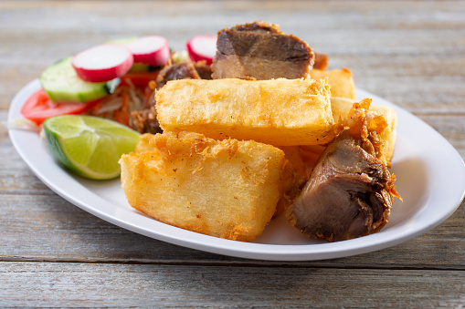 A view of a plate of yuca frita con chicharron, which is fried yuca and pork.
