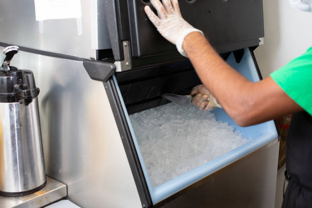 employee uses scoop A view of an employee scooping ice out of an ice machine, in a restaurant setting. machine stock pictures, royalty-free photos & images