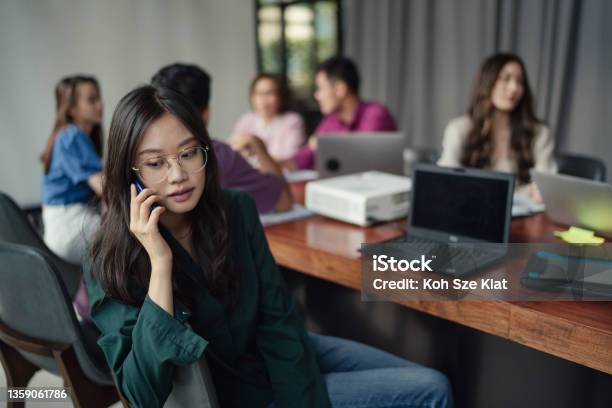 Woman Turns Away From A Meeting To Answer A Call Stock Photo - Download Image Now - Whispering, Working, Office