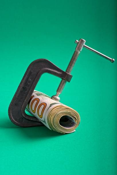istock Clamp squeezing roll of U.S. 100 dollar bills 1359066321