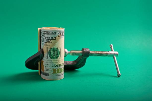istock Clamp squeezing roll of U.S. 100 dollar bills 1359066337