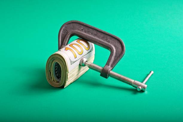 istock Clamp squeezing roll of U.S. 100 dollar bills 1359066381