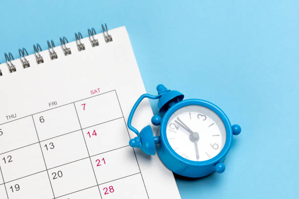 istock Alarm clock and calendar on a blue background 1359067285