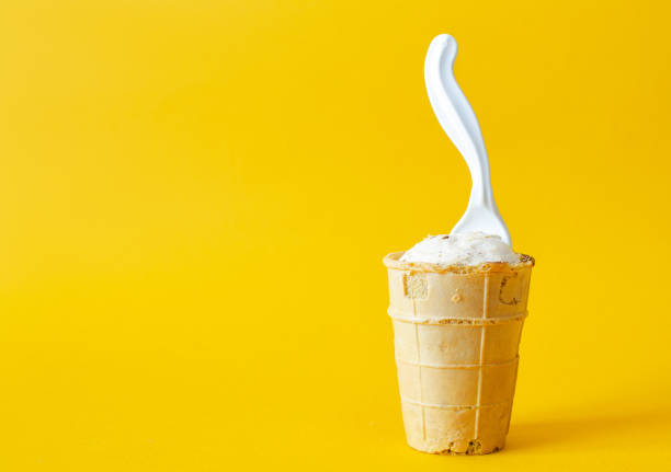 Old waffle cup with ice cream on a yellow background.