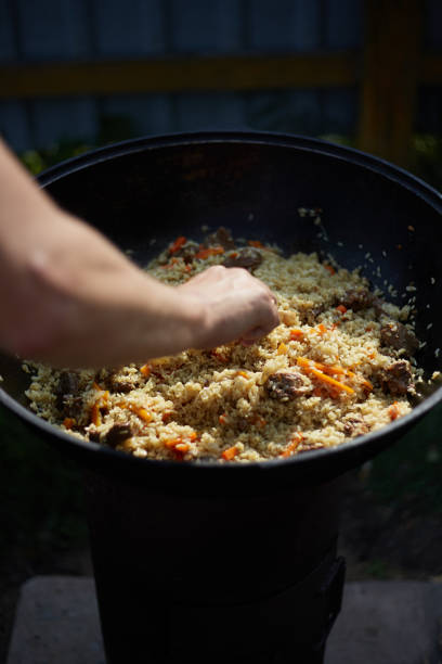 istock Cooking pilaf outdoors in a cauldron on an open fire , Asian cuisine 1359070038