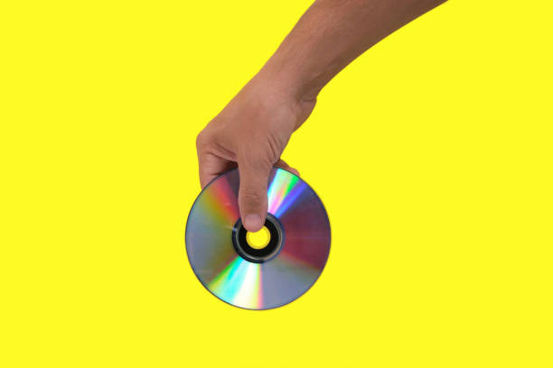 istock Scratched CD in your hand on a yellow background, outdated technologies. 1359071081