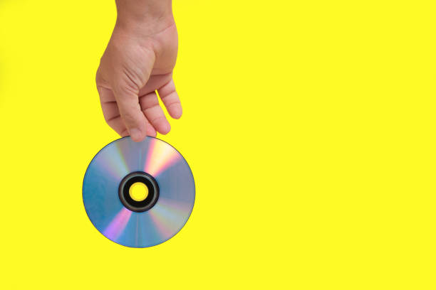istock Scratched CD in your hand on a yellow background, outdated technologies. 1359071089
