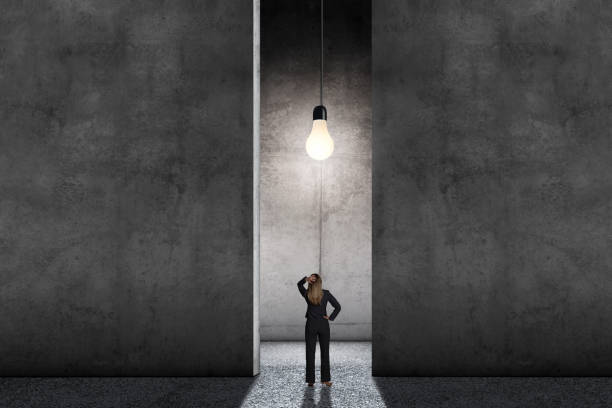 istock Woman Standing In Large Room Illuminated By Single Light Bulbf 1359071232