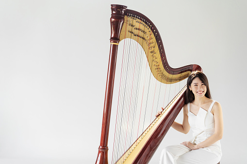 Wide shot portrait of female harpist smiling with harp
