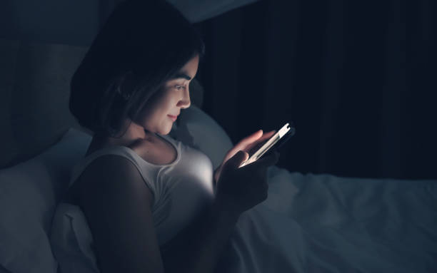 istock Woman sending messages on cellphone and lying on bed. 1359076448