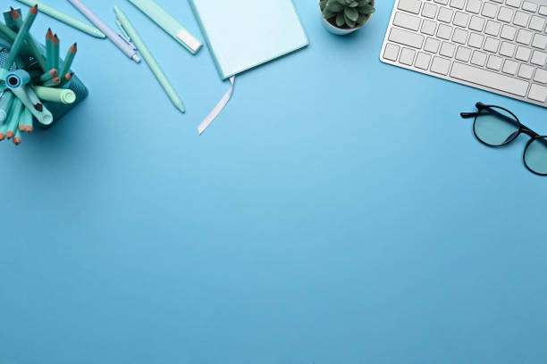 istock Creative workspace, wireless keyboard, glasses and supplies on blue background. 1359076523