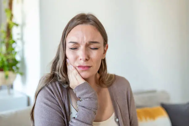 Tooth Pain And Dentistry. Young Woman Suffering From Terrible Strong Teeth Pain, Touching Cheek With Hand. Female Feeling Painful Toothache. Dental Care And Health Concept.