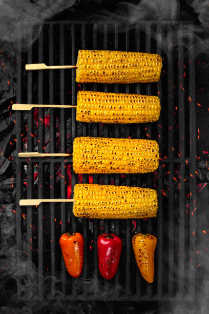 ears of corn and bell peppers cooking on barbecue grate over smouldering coals - broiling imagens e fotografias de stock