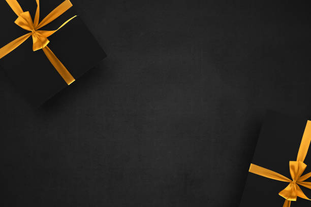 istock Black gift box with a golden ribbon with a black background 1359080945