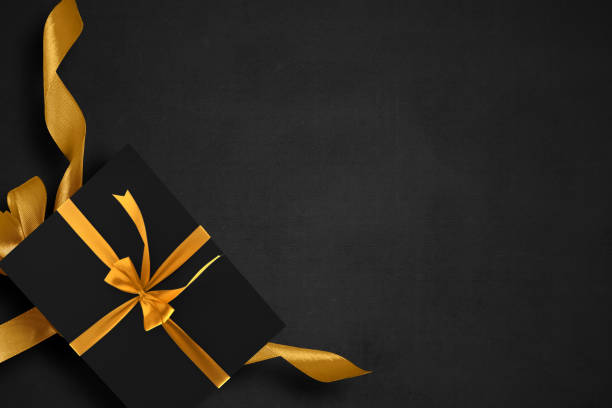 istock Black gift box with a golden ribbon with a black background 1359080953