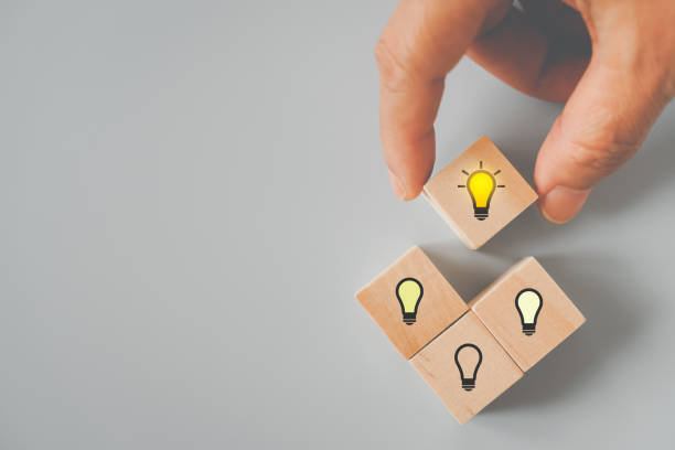 istock senior's hand choose bright light bulb icon on wooden cube for creative idea and innovation , outstanding, leadership concept 1359082934