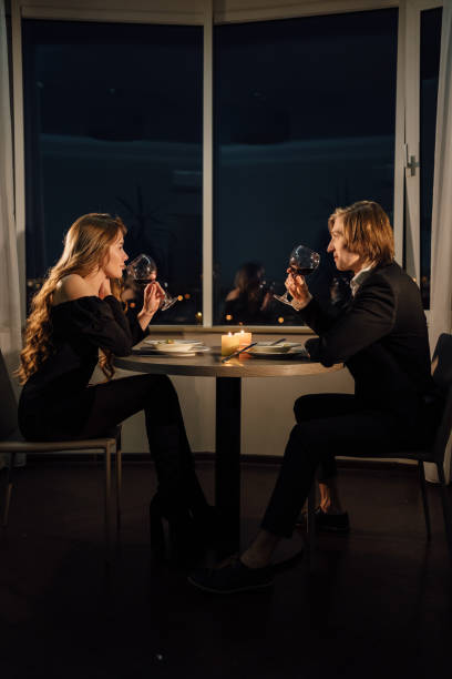 istock Romantic dinner for two couple drinking red wine, date at home at night at the table, Valentine's day celebration, man and woman relationship 1359087384