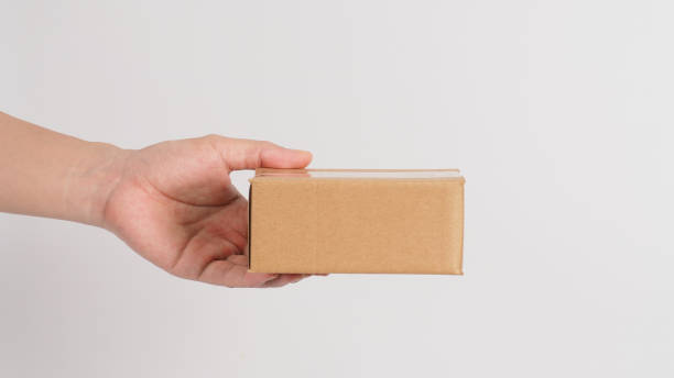 istock Hand is holding brown box isolated on white background. 1359088414