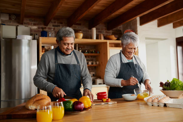 istock Multi-cultural elderly couple preparing meal in modern kitchen. Colorful vegetables for breakfast. Healthy retired lifestyle 1359089745