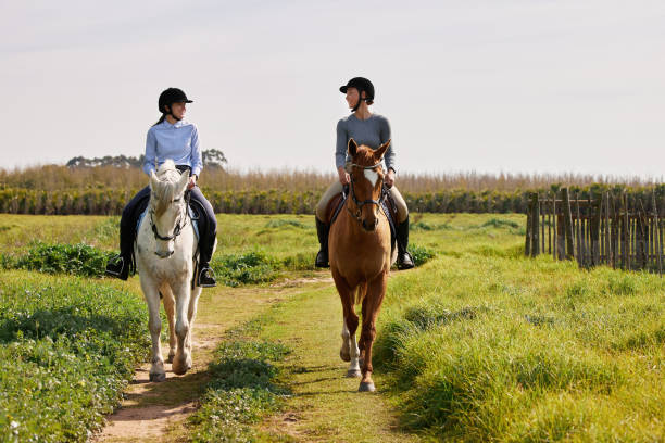 목장에서 말을 타고 있는 두 명의 젊은 여성의 전체 길이 샷 - teaching child horseback riding horse 뉴스 사진 이미지