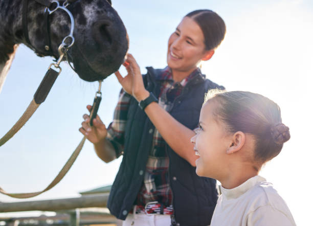 plan recadré d’une jolie jeune femme et de sa fille caressant un cheval à l’extérieur du ranch - bride women standing beauty in nature photos et images de collection