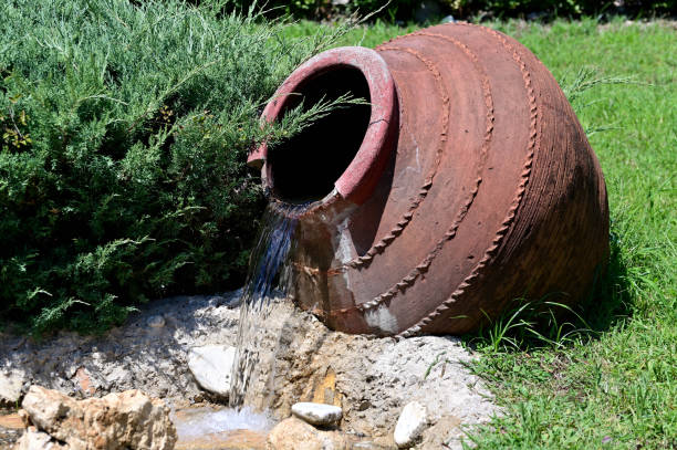 istock Water pours from a decorative amphora into a man-made pool 1359090284