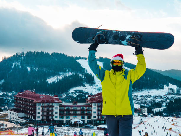istock man with snowboard in red christmas hat walking up by snowed hill 1359092720
