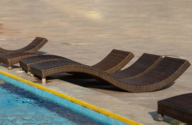opuszczone wiklinowe rattanowe leżaki o nietypowym kształcie na płytkach przed basenem - tanning bed brown relaxation resting zdjęcia i obrazy z banku zdjęć